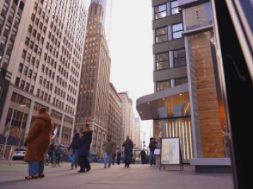 Low angle shot of NYC pedestrians walking down the street among the tall buildings of the city.